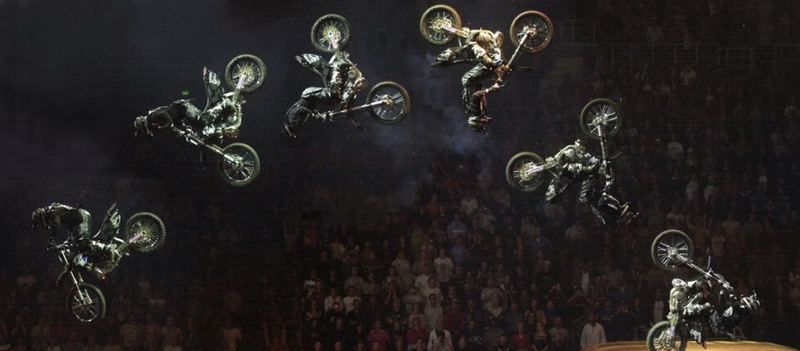A sequence of freestyle motocross backflips against a dark arena crowd