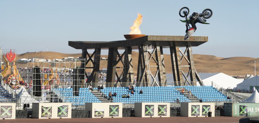 A freestyle motocross rider flips above the flaming platform at Monster X in Mongolia