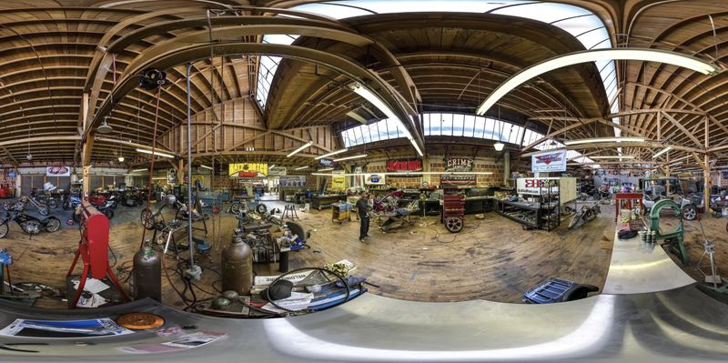 A 360 degree panorama of a custom motorcycle shop with wooden rafters and bikes in progress