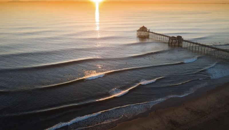 Aerial view of a pier and rolling waves at golden hour